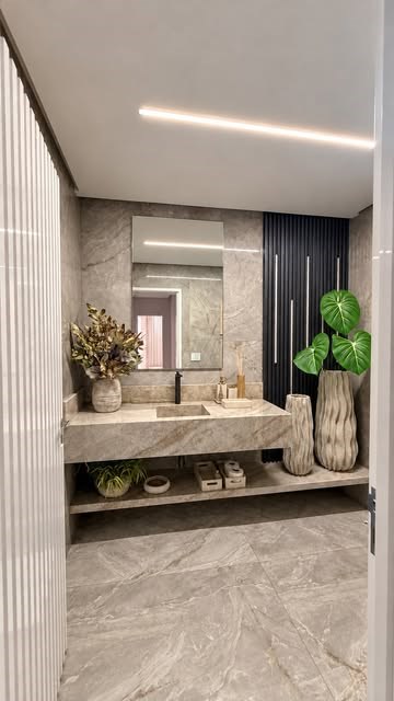 Lavabo com bancada de pedra, vasos e iluminação embutida